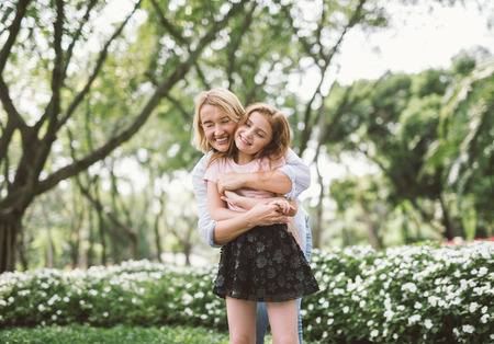 Portrait of Young Happy Beautiful Mother and Daughter Hugging. Embrace in Sunny Day on Meadowの写真素材
