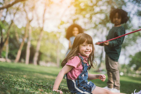 summer, childhood, leisure and people concept - group of happy kids playing with friend on green field outdoorsの写真素材