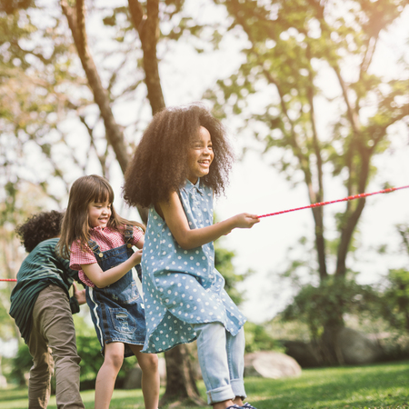 Happy children playing tug of war at the parkの写真素材