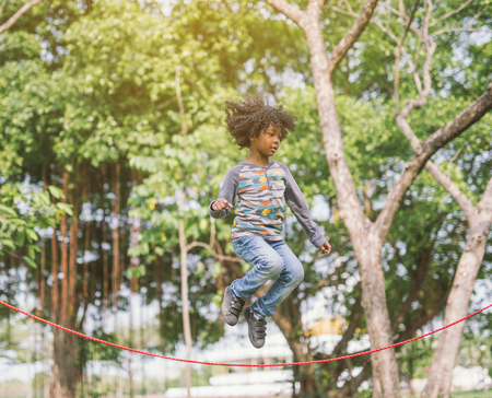 boy jumping over the rope in the park on sunny summer dayの写真素材