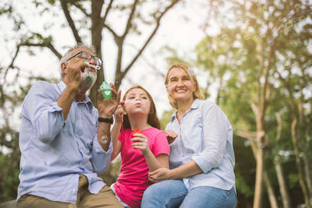 happy family in green nature park on summer ,grandfather blow soap bubbles along with grandchildrenの写真素材