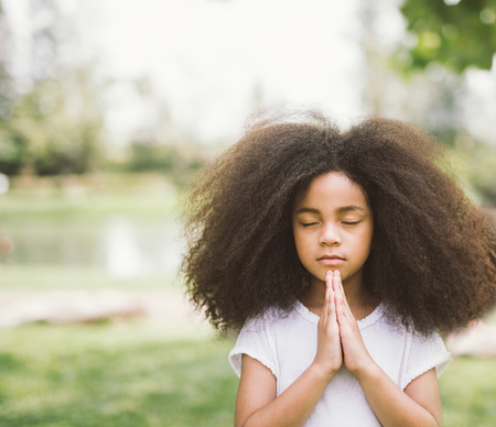 Afro child praying. Black kid prays. Gesture of faith.Hands folded in prayer concept for faith,spirituality and religionの写真素材