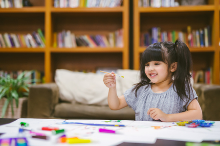 Cute little girl painting a picture at homeの写真素材