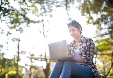 happy Asian woman using laptop at outdoor park Garden.の写真素材