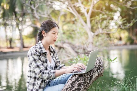 happy Asian woman using laptop at outdoor park Garden.の写真素材