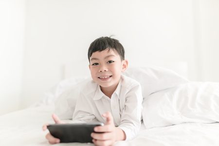 Kid with smartphone in the bedroom indoor.の写真素材