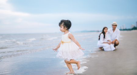 Parent see daughter playing  on the beach. girl playing with familyの写真素材
