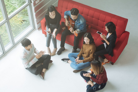 Happy Asian teenager friends enjoying singing and playing guitar at homeの写真素材