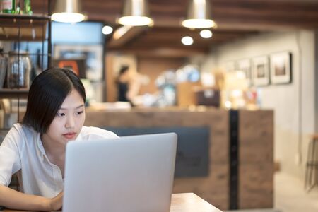 Young Asian woman working with a laptop in the coffee shop cafe office.の写真素材