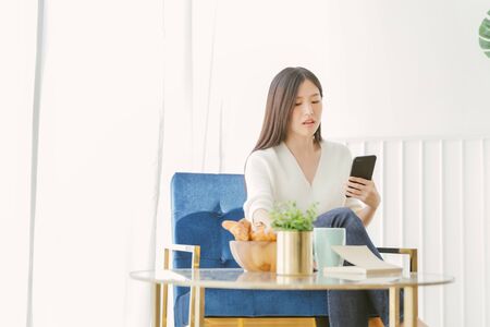 Portrait Asian woman reading book and relaxing with coffee at homeの写真素材