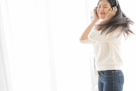 Asian women relax by listening to music using headphones and dancingの写真素材