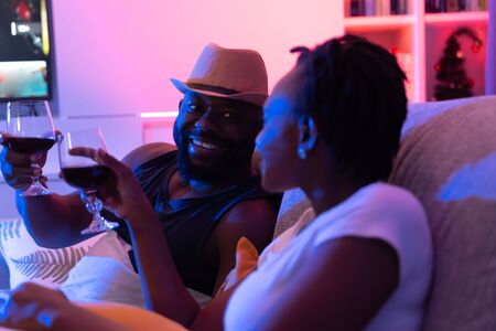 African couple enjoying wine and watching movies at home.の写真素材