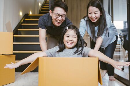 Portrait of happy Asian family moving to new house with cardboard boxes.の写真素材