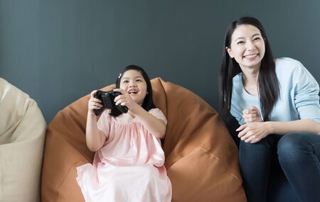 little girl and parent family playing video game at homeの写真素材