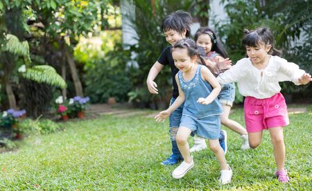 Asian kids playing outdoors with friends. little children play football soccer at nature park.の写真素材