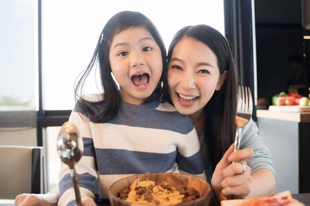 mom and daughter eating Cereals with milk having breakfast in kitchen.の写真素材