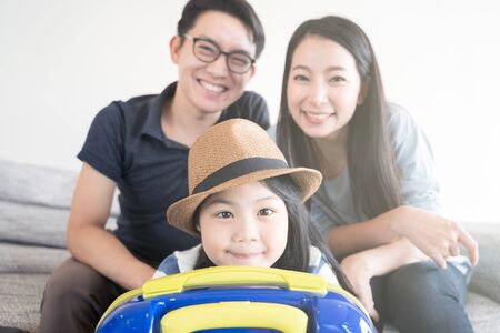 Happy Asian family is preparing for travel at home .Mom daughter and father are packing suitcases for the trip.の写真素材