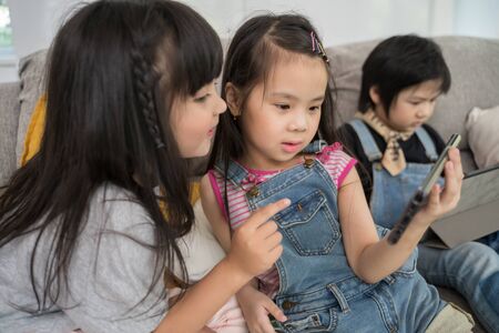 group of little children watching film movie cartoon together on digital tablet and phone. Kids...