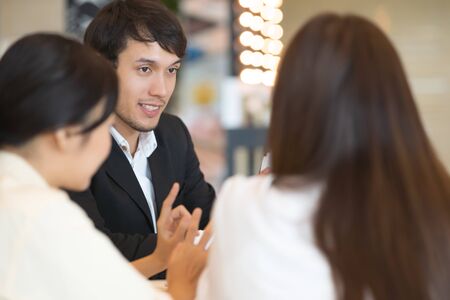 Young Asian man and business people are meeting in office discussion with colleagues . Group of Business team working and share ideas about project to partnersの写真素材
