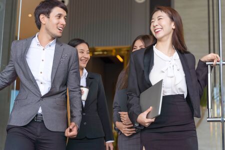 Asian business people walking to go out office building. Young businessman and businesswoman talking and Open the office door.の写真素材