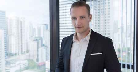 Portrait of successful young businessmanÂ at office city building view