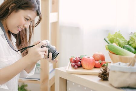 Asian woman using camera Taking pictures to vegetables on table kitchenの写真素材