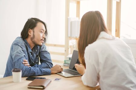 two Asian people talking discussion and show detail on laptopの写真素材