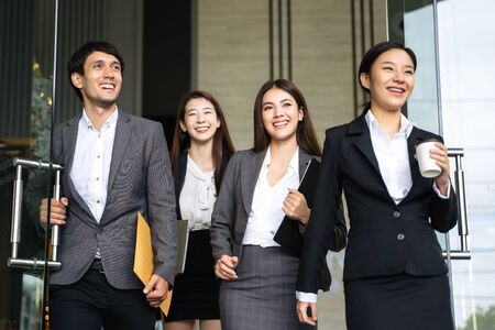 Asian business people walking to go out office building. Young businessman and businesswoman talking and Open the office door.の写真素材