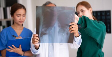 Team of Asian doctor examining chest x-ray film of patient at hospital.