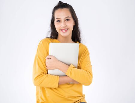 Young happy Asian student woman holding laptop on white backgroundの写真素材