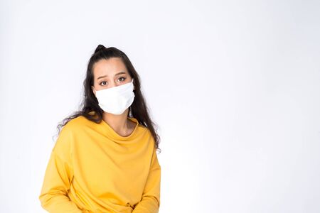 Young Worry Asian woman wearing hygienic mask to prevent infection corona virus Air pollution pm2.5 she wearing a yellow sweater shoot in shot isolated on white backgroundの写真素材