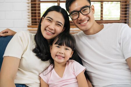 Portrait of happy Asian family spending time together on sofa in living room. family and home concept.の写真素材