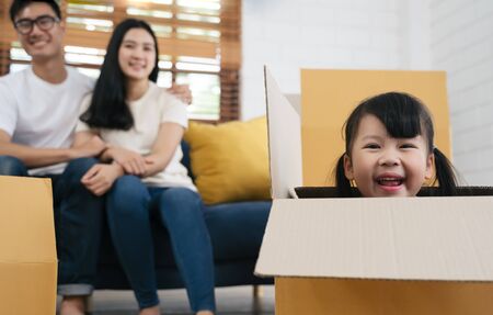 Portrait of happy Asian family moving to new house with cardboard boxes and playing cardboard boxの写真素材