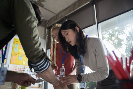 Asian female creative designers present their work to the team. Designers are meeting in a modern...