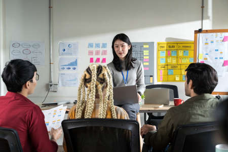 Asian female creative designers present their work to the team. Designers are meeting in a modern...