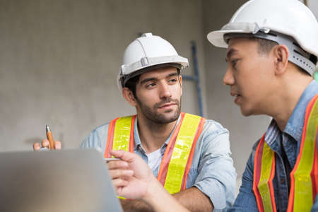 The engineering team working at building site meeting and discussing on laptop . Team onsite of architecture inspector and discuss togetherの写真素材