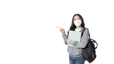 Young Asian college student wears face mask and Hoodie Sweatshirt with laptop and backpack isolated over white backgroundの写真素材