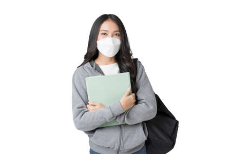 Young Asian college student wears face mask and Hoodie Sweatshirt with laptop and backpack isolated over white backgroundの写真素材