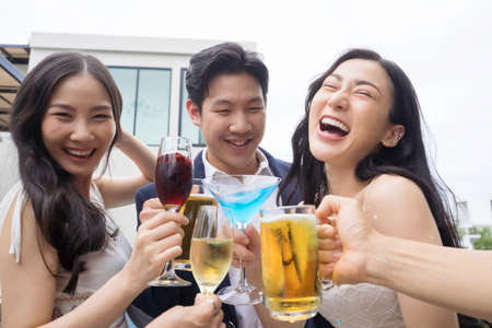 Young asian friends toasting drinks at a partyの写真素材