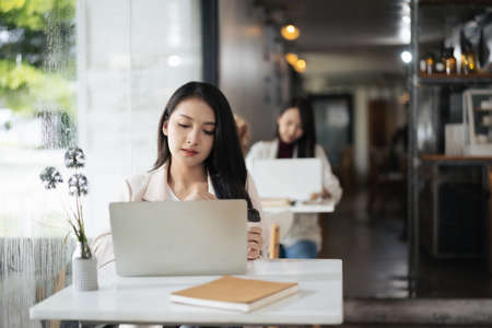 Young Asian woman using laptop in coffee shopの写真素材