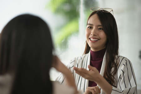 Two young Asian women friends talking at a coffee shopの写真素材