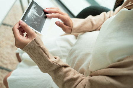 Pregnant woman showing ultrasound picture at home