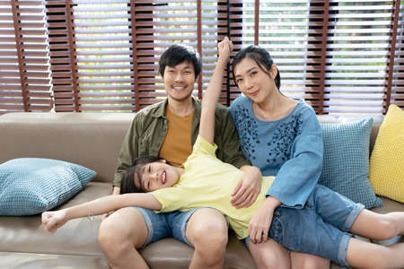 portrait of happy Asian family spending time together on sofa in living room. family and home concept.の写真素材