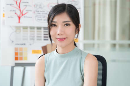 Close up portrait young Asian woman smiling in officeの写真素材