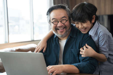 Happy Asian middle aged man and son at home.の写真素材