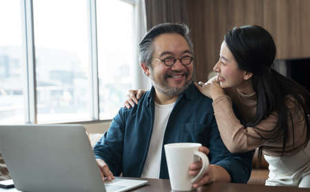 Middle-aged Asian Wife encourages cheerful husband to work.の写真素材