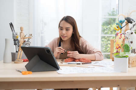 Young Asian girl making a sculpture with modeling clay form learn from the internet online at home...
