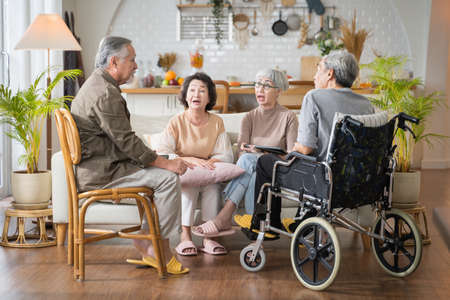 Group Asian seniors friends are sitting in the living room of a home together, enjoying talking together.の写真素材