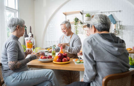 Group of Asian senior people friends making fruit juices for friends to drink in kitchen.colorful fruits and vegetables. Healthy eatingの写真素材