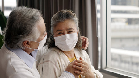 Two elderly Asian couples wearing masks hug and encourage each other.の写真素材